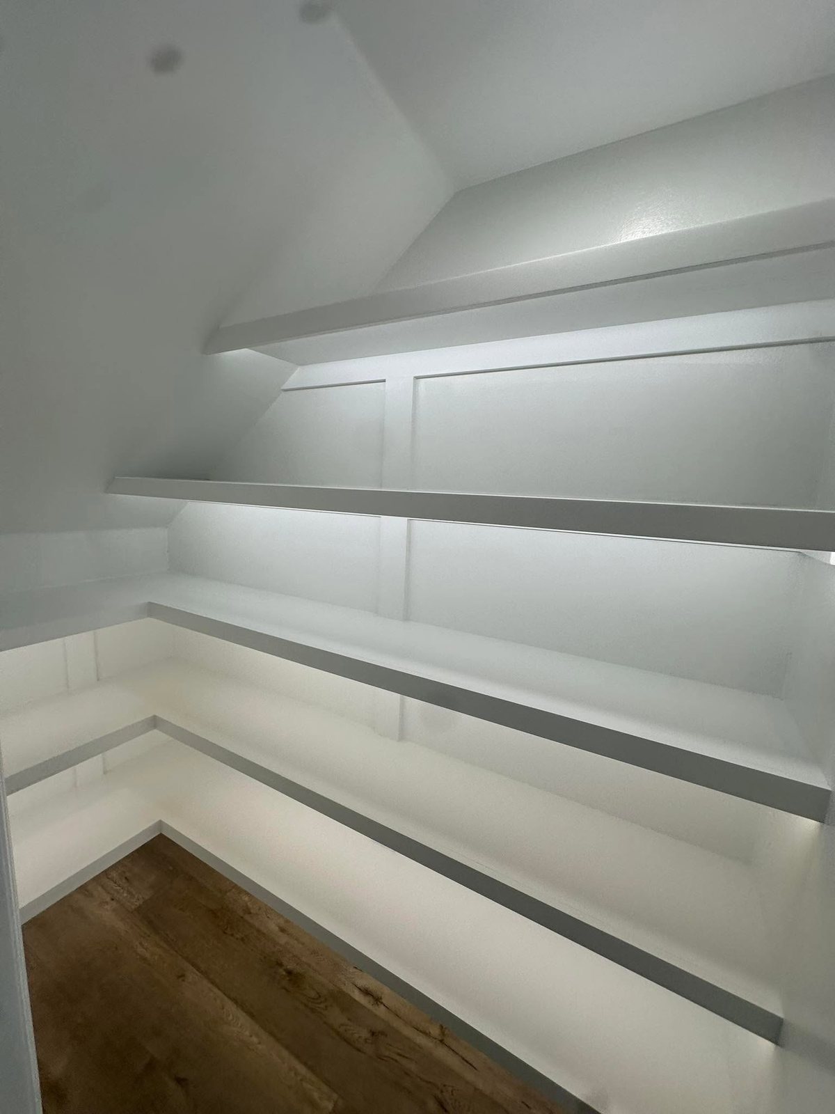 Finished custom pantry with clean white shelving and lighting